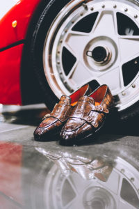 handmade crocodile loafers rest against a Ferrari F40
