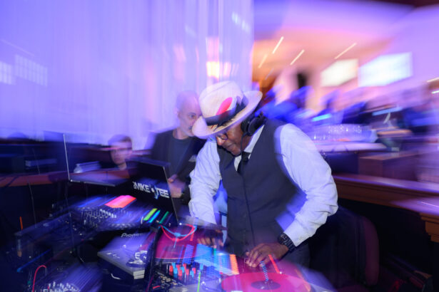 A DJ wearing a hat and headphones mixes music on turntables in a vibrant, colorful club setting with blurred lights and people in the background. South Florida Business & Wealth