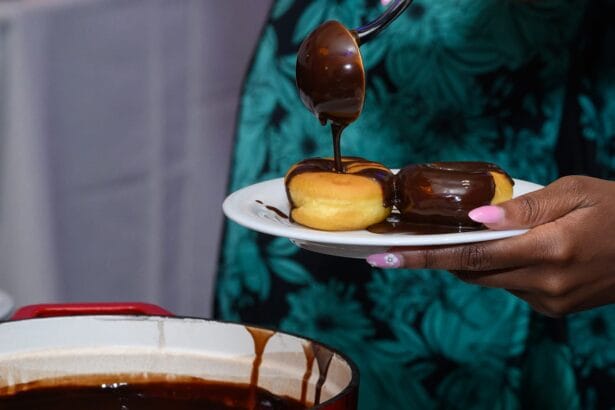 A person holds a plate with two doughnuts while pouring chocolate sauce over them with a spoon; a pot of chocolate sauce is visible below. South Florida Business & Wealth