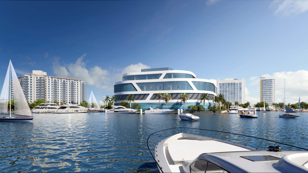 A modern, multi-story building with a curved design sits by the waterfront, surrounded by palm trees, sailboats, and yachts on a sunny day, with several high-rise hotels in the background. South Florida Business & Wealth