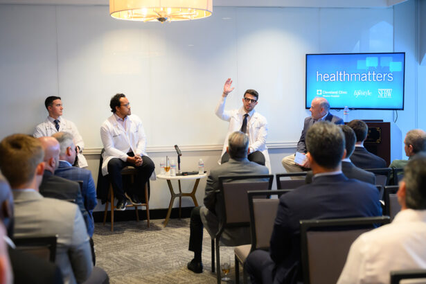A panel of four men, three in white coats, discuss health topics in front of an audience. One panelist gestures while speaking. A screen behind them displays "healthmatters" and Cleveland Clinic logos. South Florida Business & Wealth