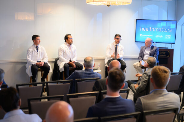 Four men, two in white lab coats and two in suits, sit on a panel in front of an audience. A screen behind them displays "healthmatters." The setting appears to be a professional seminar or discussion event. South Florida Business & Wealth