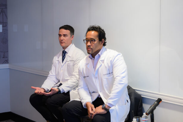 Two men in white lab coats sit side by side in a bright room, one with hands open in a speaking gesture, the other with hands on his lap; both appear focused and attentive. South Florida Business & Wealth