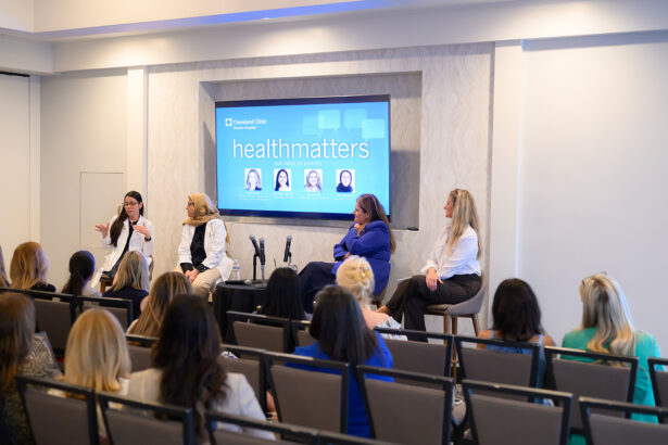 A panel of four women speaks to an audience at a health event, with a large screen behind them displaying "healthmatters" and speaker photos. The room is brightly lit and filled with seated attendees. South Florida Business & Wealth