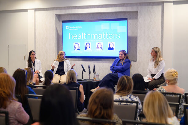 A panel of four women speak on stage during a Cleveland Clinic event called "healthmatters," with an audience seated in front of them and a large display screen behind showing the event title and panelist photos. South Florida Business & Wealth