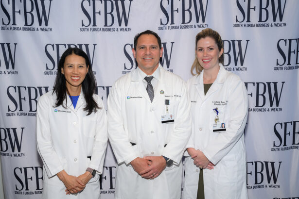 Three doctors in white lab coats stand smiling in front of a step-and-repeat banner with the logo "SFBW South Florida Business & Wealth. South Florida Business & Wealth