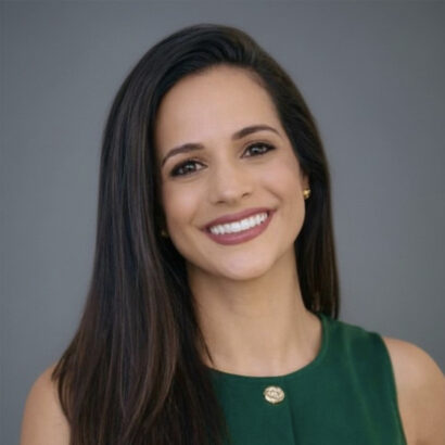 A woman with long dark hair wearing a sleeveless green top smiles at the camera against a plain gray background. South Florida Business & Wealth