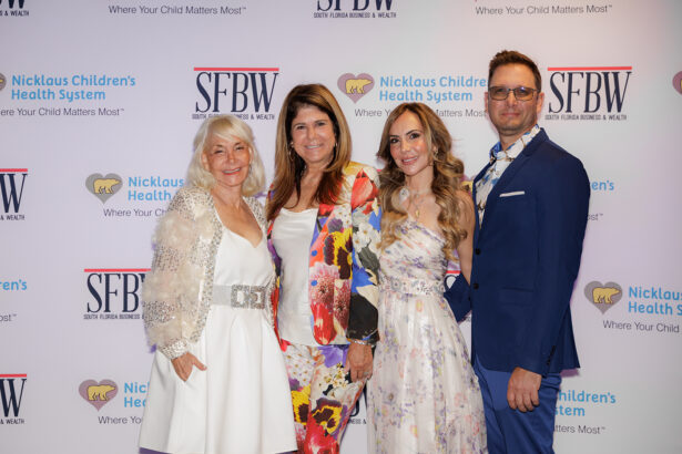 Four adults dressed in formal attire pose together, smiling, in front of a step-and-repeat banner with logos for SFBW and Nicklaus Children’s Health System. South Florida Business & Wealth