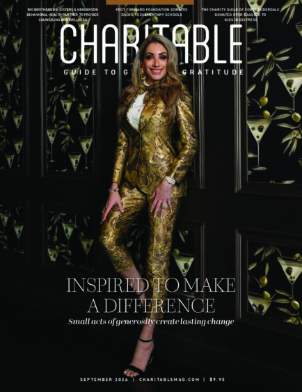 A woman in a gold patterned suit stands smiling in front of a wall with martini glass designs. The magazine cover reads, "Charitable: Guide to Giving & Gratitude" and "Inspired to Make a Difference. South Florida Business & Wealth
