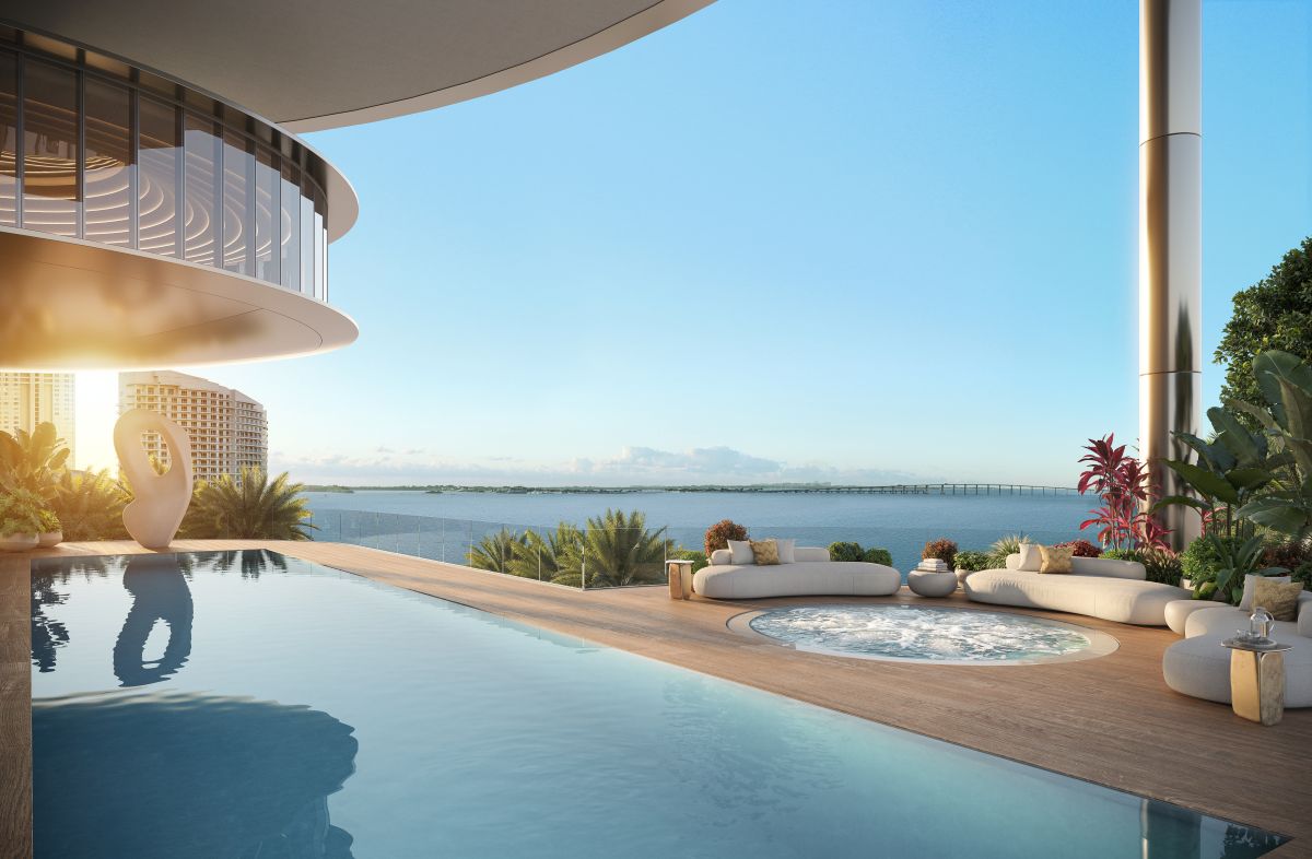 Luxury infinity pool and hot tub on a modern terrace overlooking the ocean, surrounded by lush plants and contemporary architecture, with a glass railing and a clear sky at sunset. South Florida Business & Wealth