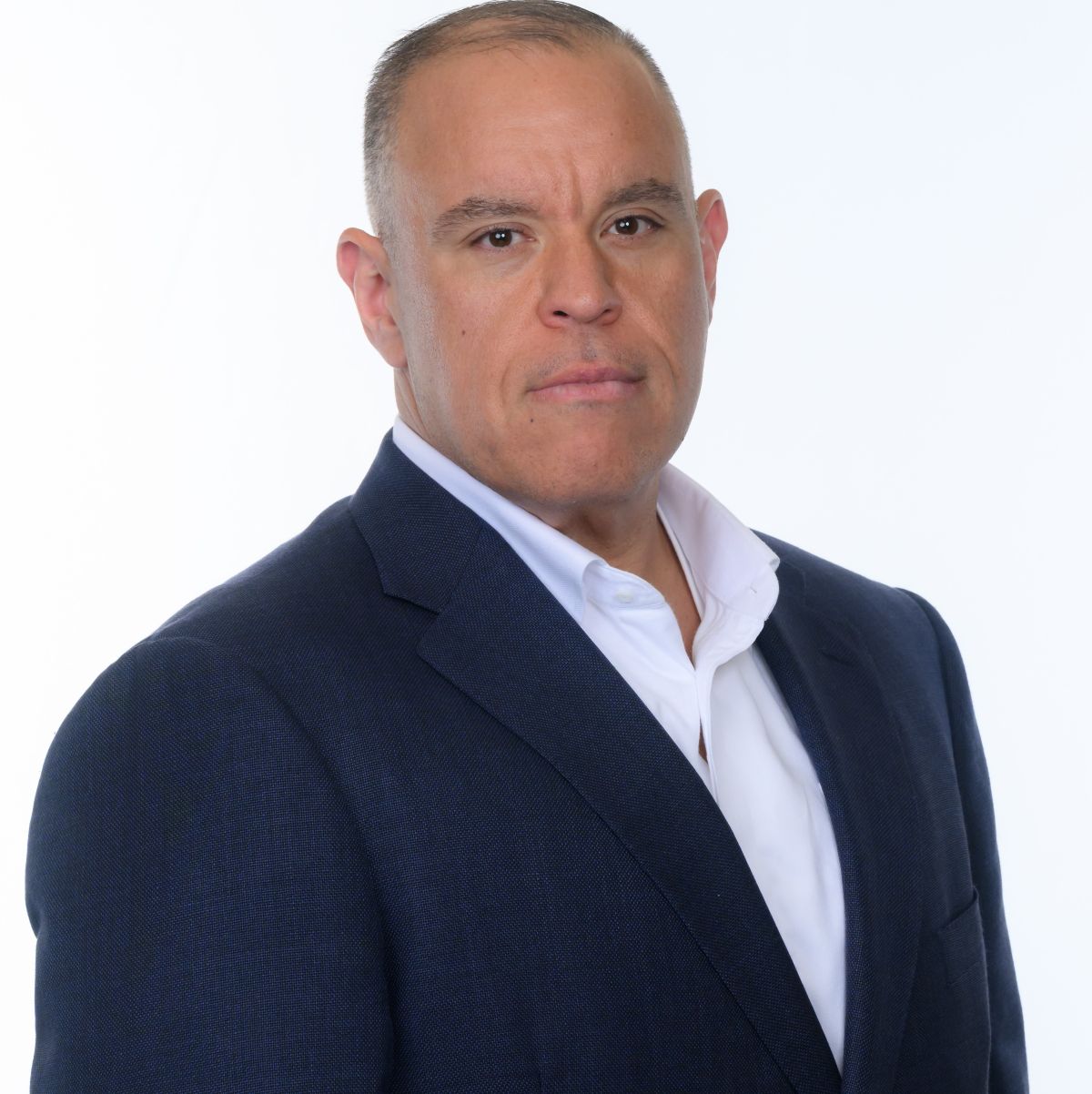 A man wearing a dark blue suit and white shirt poses against a plain white background, looking directly at the camera with a neutral expression. South Florida Business & Wealth