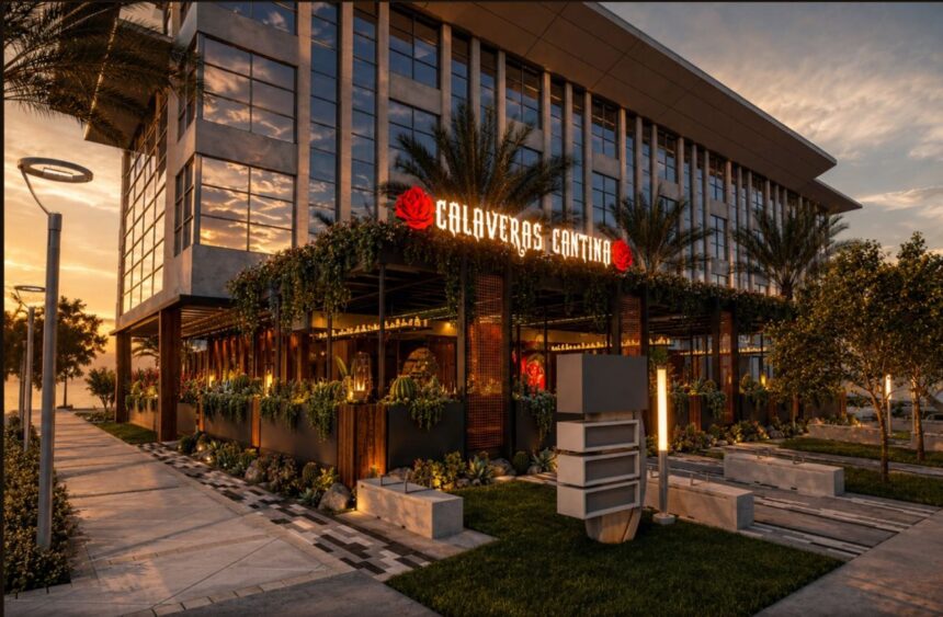 A modern building at sunset features "Calaveras Cantina" in red neon letters, surrounded by greenery, palm trees, and outdoor lights along a landscaped pathway. South Florida Business & Wealth
