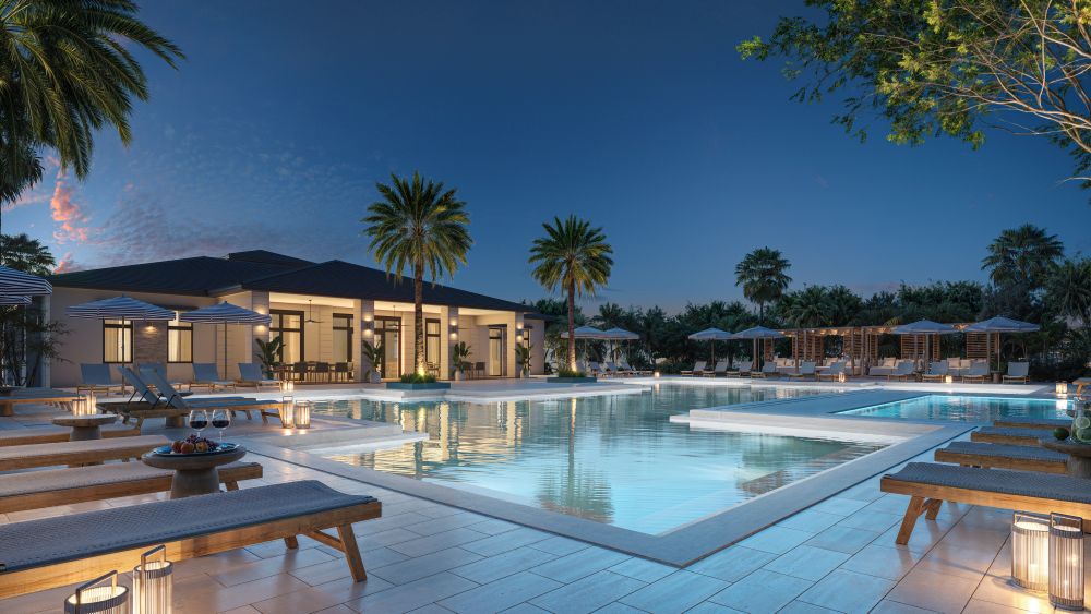 Luxurious outdoor swimming pool area at dusk with lounge chairs, umbrellas, palm trees, lanterns, and a modern building in the background. The pool reflects the evening sky, creating a serene atmosphere. South Florida Business & Wealth