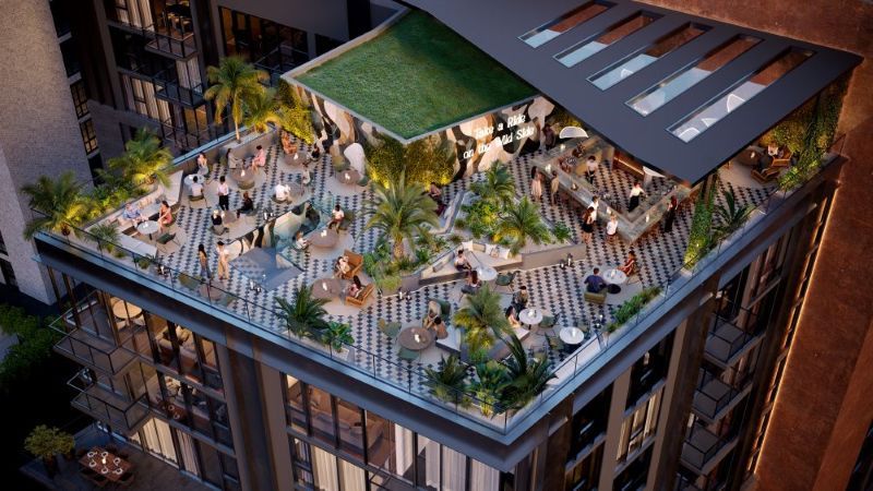 A rooftop restaurant with a green roof, palm trees, and people dining at tables. The floor has a checkered pattern, and the space is stylishly decorated with plants and modern furniture. South Florida Business & Wealth