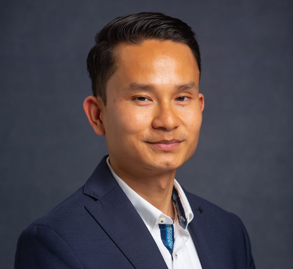 A man in a navy blue suit jacket and white collared shirt looking toward the camera. South Florida Business & Wealth